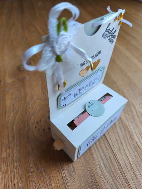 Schachtel mit Schleife und einem Anhänger, enthält ein kleines Geschenk oder eine Botschaft.