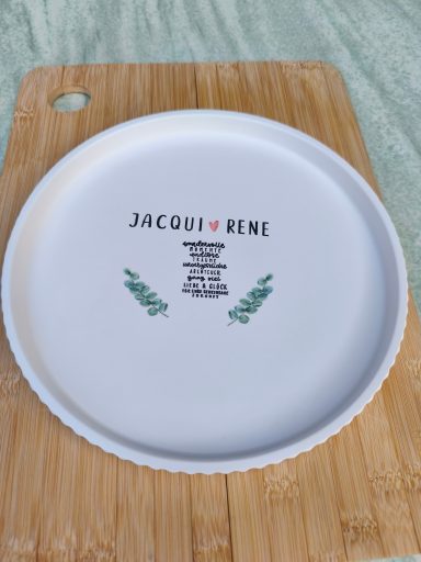 Weißer Teller mit dem Aufdruck "JACOBI ♥ RENE" und grünen dekorativen Elementen.