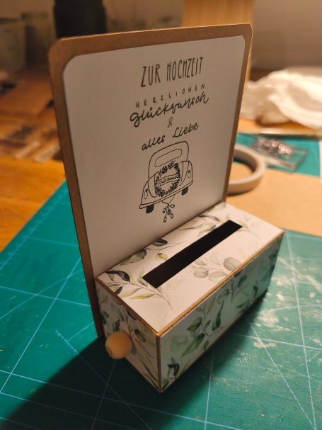 Ein kleiner Spendenkasten mit Illustrationen und einem eingeklebten Deckblatt.